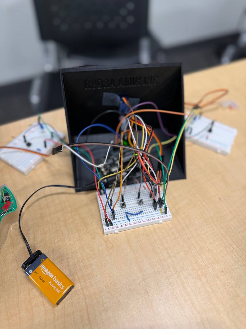 A black 3D-printed case with a breadboard and dozens of jumper wires behind it, connected to a 9V battery.